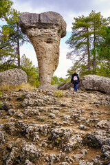 Woman walking next to the incredible eroded rock formation of the Enchanted City of Cuenca.