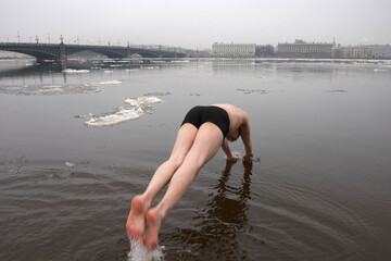 A man jumps into the Neva River in St. Petersburg in winter to swim.