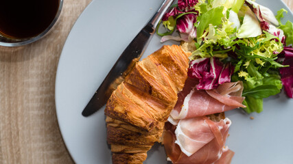 Breakfast with coffee, croissant, with ham and fresh green salad. Health food concept. Top view. Long format banner.
