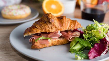 Breakfast with coffee, croissant with ham and fresh salad, orange and pear. Close up. Long banner format.