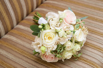 Wedding rings lie on a wedding bouquet of roses and other flowers