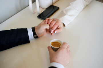 Male and female hand in a handshake on the background of the table. Hand with a cup of coffee