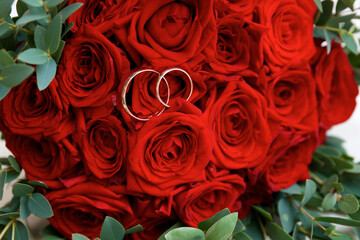 Wedding rings lie on rose flowers in a bouquet
