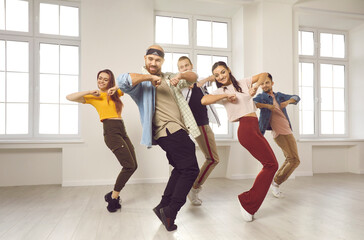 Energetic diverse group of dancers in casual clothes learn moves on lesson or class in studio....