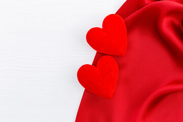 Red satin and two heart on white wood background
