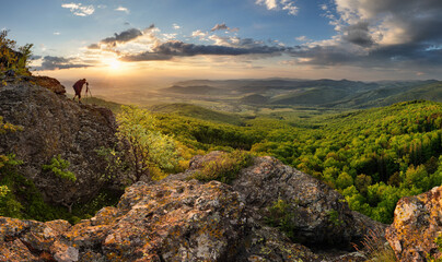 Fototapeta na wymiar Male photographer on the mountain top with green landscape