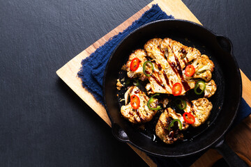 Food concept Roasted organic Cauliflower in skillet iron pan on black slate stone back ground with copy space
