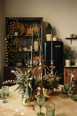 Rustic kitchen, serving wooden table and green vintage glasses with candles