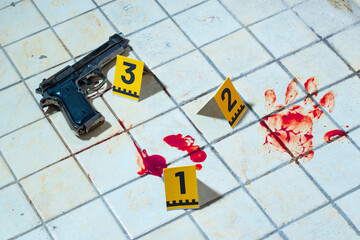 Crime scene investigation with a gun, blood stains, hand print and yellow evidence markers on old...