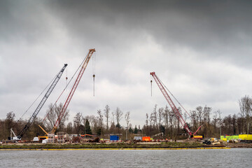 Fototapeta na wymiar Tower cranes works on building site on the dramatic sky background
