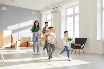 Happy young family with little children bring boxes enjoy moving day to new home. Smiling parents with small kids unpack unbox relocate to own house. Rent and realty, real estate concept.