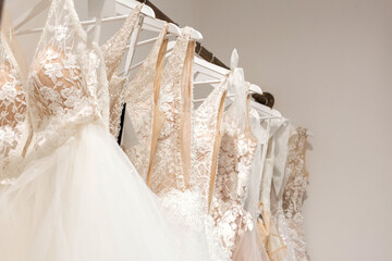 Assortment of dresses hanging on a hanger on the background studio. Fashion wedding trends. Interior of wedding shop
