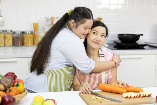 down syndrome teenage girl hugging her mother in the kitchen