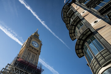 Fototapeta na wymiar Historic and Iconic restored Big Ben after conservation works in 2022 with blue and gold color scheme next to a modern architecture building