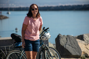 A Beautiful Mature Woman at Dana Point, California, Taking a Break from Riding Her Bike - obrazy, fototapety, plakaty
