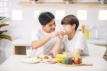 Obraz na płótnie Canvas gay man feed milk to his partner during breakfast