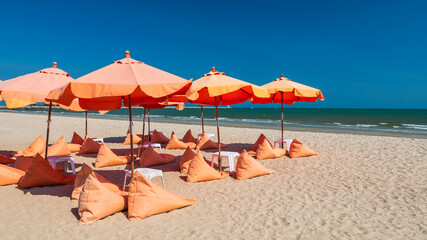 Orange umbrellas and bean bag chairs on sand beach