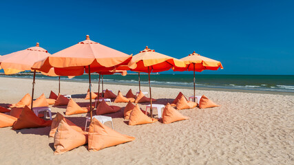 Orange umbrellas and bean bag chairs on sand beach © Blanscape