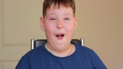 The fat boy rubs his eyes with his hands, opens his mouth in surprise. He's sitting on a chair.