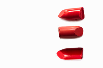 Samples of red lipsticks broken on a white background. Texture of cosmetic products
