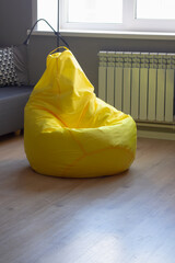 A bright yellow bag chair in a room with gray walls