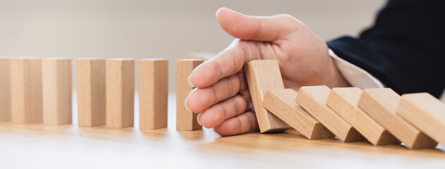 Protection finance from domino effect concept. Hands stop domino effect before destroy stack of...