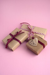 gifts for valentine's day. three gift boxes, a wooden heart on a pink background. vertical photo. 14 february, mother's day