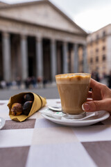 filiżanka cappuccino trzymana przez damską rękę. kawa wśród rzymskich antycznych zabytków. kawa, espresso, włoskie śniadanie 