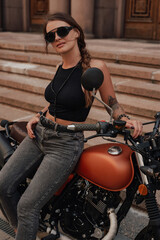 Fototapeta na wymiar Stylish woman dressed in dark clothes with retro bike
