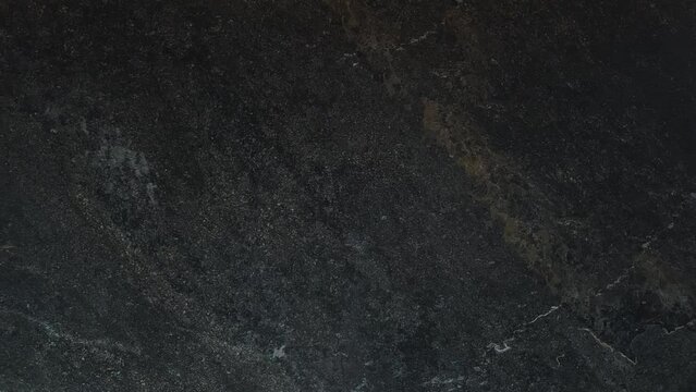 Dark natural background of textured marble wall. Close-up view.