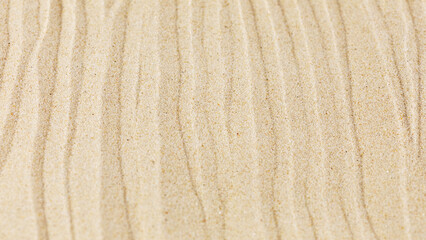 Fototapeta na wymiar Wavy sand texture background. Dented sande waves of the blow of the wind. Sand wave pattern on a beach