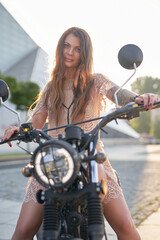 Attractive woman biker with tattoos sitting on retro motorbike