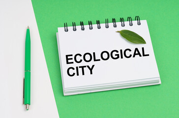 On a white-green background lies a pen, a leaf of a plant and a notepad with the inscription - Ecological City