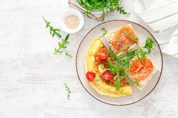 Omelette or omelet, fresh arugula and tomato salad and toasts with butter and salted salmon....