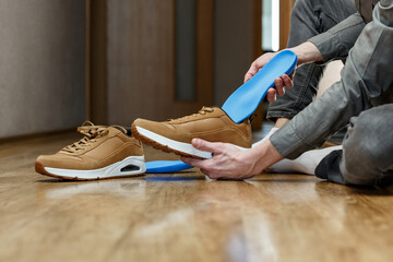 Man putting new custom insole in a shoe. - obrazy, fototapety, plakaty