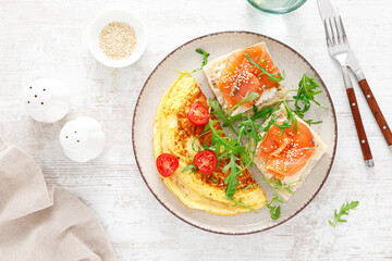 Omelette or omelet, fresh arugula and tomato salad and toasts with butter and salted salmon. Breakfast. Top view
