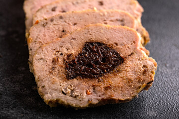Tasty homemade slices of meatloaf with prunes on rustic background
