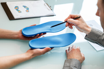 Doctor consulting patient on custom orthotic insoles in a clinic for a personalised custom fit. - 485391188