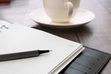 Close-up of a pen on a notepad against the background of a coffee cup