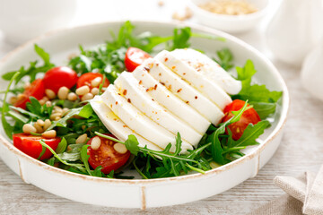 Salad with arugula, mozzarella cheese and pine nuts. Breakfast. Ketogenic, keto or paleo diet. Healthy food