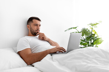 Busy serious concentrated millennial muscular european man typing on computer, create idea,...