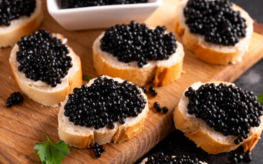 Slices of bread with black caviar on rustic dark background
