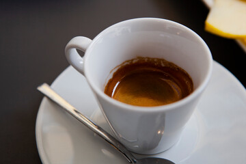 Traditional Italian breakfast. Small white ceramic cups with espresso (coffee) on a table with a saucer and a metal spoon at a local bar (coffee shop) in Milan, Lombardy, Italy. European drinks.