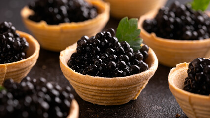Tartlets with black caviar on rustic background