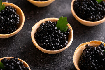Tartlets with black caviar on rustic background