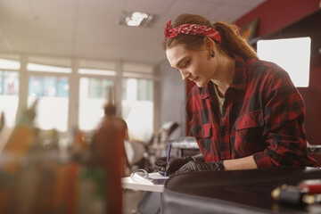 Portrait of concentrated woman drawing something while sitting in tattoo salon