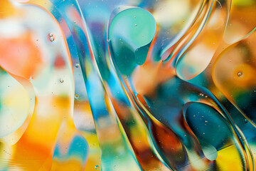 Close-up of the movement of oil droplets on the water surface. Colorful abstract macro background of oil drops on the water surface.