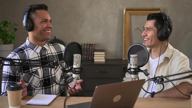 Two man hosting online podcast, discuss social media, talk into microphone Spbd. Recording broadcast at home with laptop. Dj smiles and host communicate with colleague