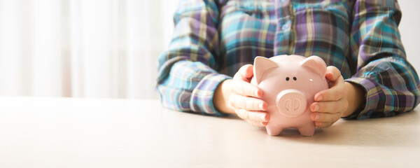 Obraz na płótnie Canvas woman hand putting money coin into piggy for saving money wealth and financial concept