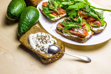 Sandwiches with avocado, trout and sour cream, sprinkled with spicy dill. Celery leaves.